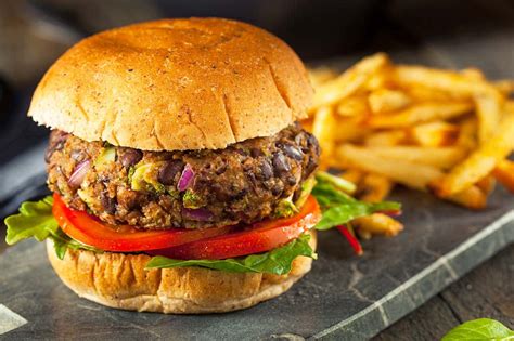 Un plato apetitoso con una hamburguesa vegana casera bien formada, acompañada de patatas fritas y ensalada.