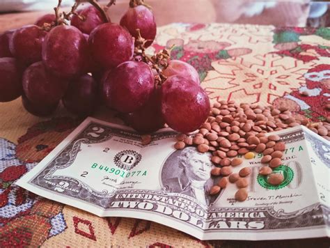 Mesa de Año Nuevo con uvas, lentejas y un billete en un zapato, representando tradiciones para la buena fortuna