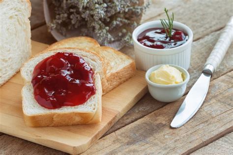 Foto de pan casero con manteca, rebanado y untado con mermelada o queso.