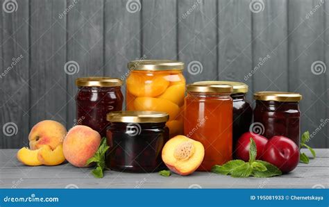 Mermeladas de diferentes frutas en frascos de vidrio, con frutas frescas alrededor