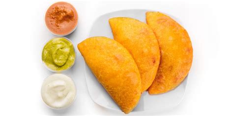 Una vista aérea de un puesto callejero de empanadas venezolanas con varios clientes haciendo fila.