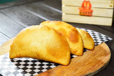 Infografía detallando los pasos para formar y freír una empanada venezolana.