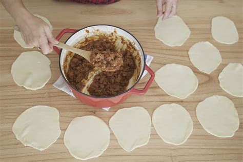 Proceso de armado de empanadas, colocando relleno y sellando bordes