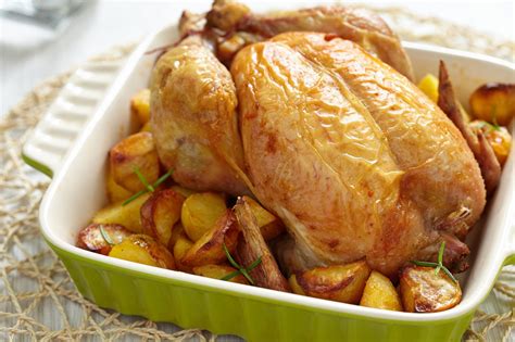 Plato terminado de pollo al horno con patatas doradas y jugosas, presentado de forma apetitosa.