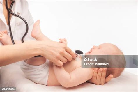 Médico pediátrico examinando el abdomen de un bebé con un estetoscopio.