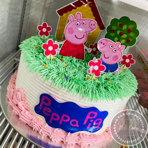 Torta de Peppa Pig decorada con crema, bordes de pasto verde y flores