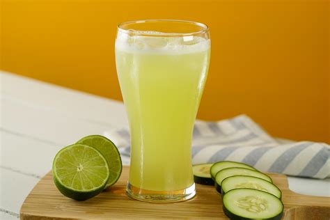 Vaso de jugo de pepino fresco con rodajas de pepino y limón, destacando sus beneficios saludables