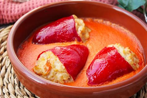 Plato de pimientos del piquillo rellenos con una suave salsa cremosa y decoración de hierbas aromáticas