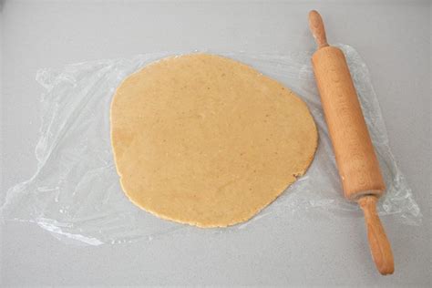 Mesa de cocina con masa de galletas estirada y herramientas improvisadas para cortar
