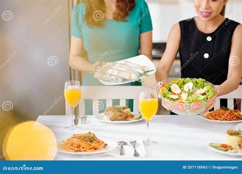Una mujer sonriente sirviendo un plato de ensalada de fideos de arroz en un puesto de comida al aire libre.