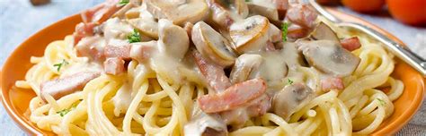Plato de pasta cremosa con tocino y champiñones decorado con perejil fresco