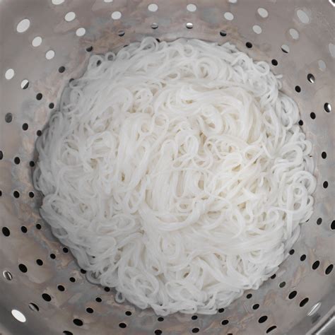 Fideos de arroz secos en remojo en agua caliente