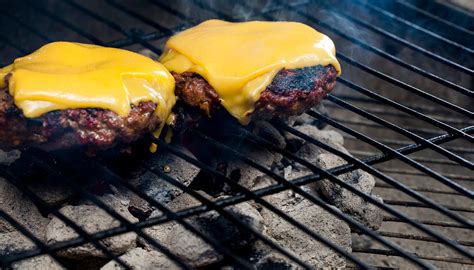 Hamburguesas cocinándose en una plancha con queso
