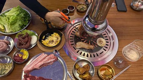Esquema visual de una mesa de barbacoa coreana con la parrilla central y diversos acompañamientos (banchan) alrededor.