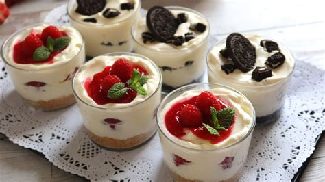 Vasitos de tarta de queso individuales, decorados con mermelada y fruta fresca.