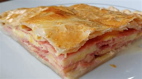 Imagen de un pastel de jamón y queso recién horneado y cortado en porciones.
