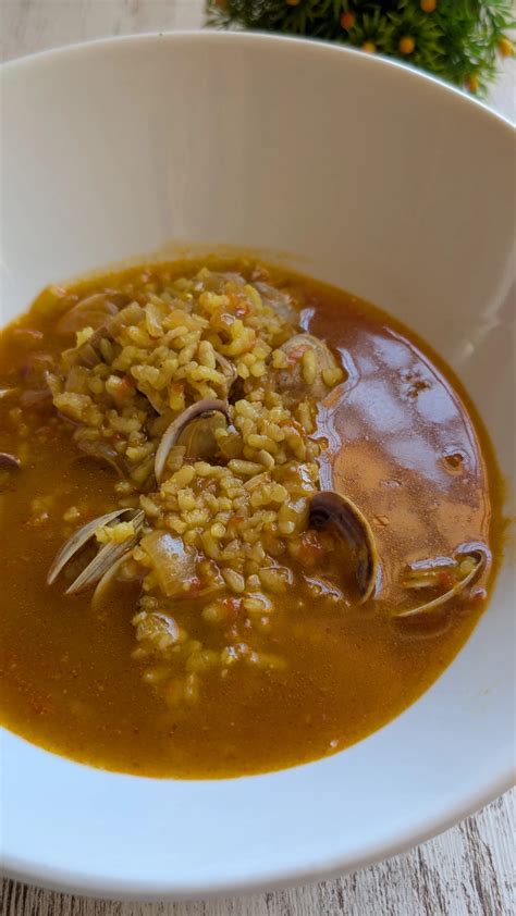 Plato de arroz con almejas servido en la mesa con limón y pan
