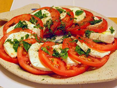 Plato de ensalada Caprese con rodajas de tomate, mozzarella y albahaca fresca dispuestas armoniosamente