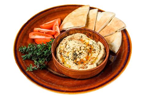 Foto de hummus de garbanzos en un bol, decorado con pimentón y perejil, con pan de pita alrededor