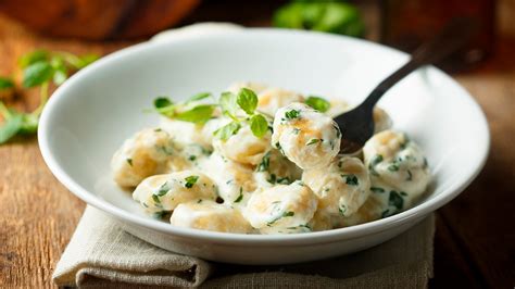 Plato de gnocchi con salsa de quesos y hierbas frescas