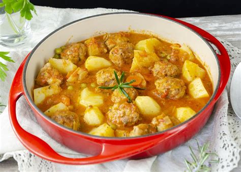 Plato de albóndigas en salsa de curry con patatas fritas y gajo de lima