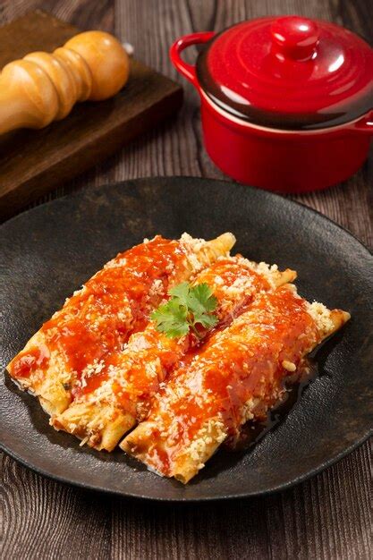 imagen de panqueques rellenos cubiertos con salsa y queso horneados