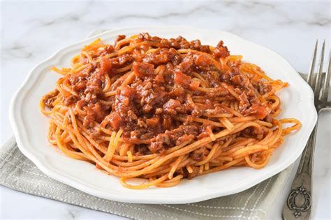 Ilustración apetitosa de un plato de spaghetti con salsa boloñesa, mostrando la textura de la carne y la pasta.