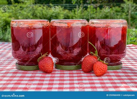 Fotografía de frascos de mermelada casera recién envasados y boca abajo.