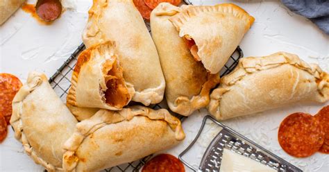 Empanadillas de pizza recién hechas y doradas, cortadas para mostrar el relleno de queso y pepperoni