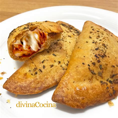 Gran empanada de pizza horneada, dorada y cortada en porciones, mostrando el abundante relleno