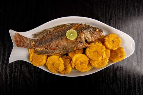 Pescado blanco frito en salsa agridulce de piña, acompañado de fideos y decorado con cilantro fresco