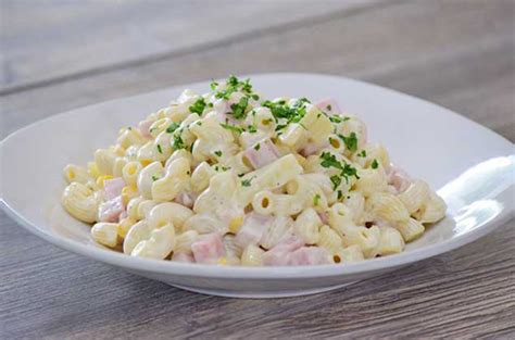 Plato de pasta de codito mezclado con jamón de pavo en cubos y piña, bañado en una salsa cremosa