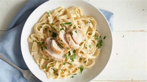 Plato de pasta con pollo en salsa blanca, decorado con perejil