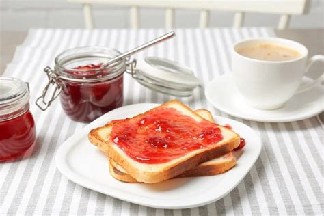 Mesa con frascos de mermelada casera variada y tostadas con mermelada de frutilla