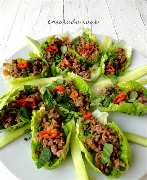 Ingredientes frescos para una ensalada Laab tailandesa, incluyendo carne picada, hierbas frescas y cebolla.