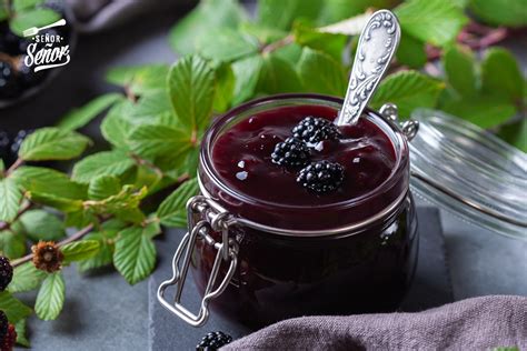 Mesa con ingredientes para mermelada: moras frescas, azúcar, limones y una olla