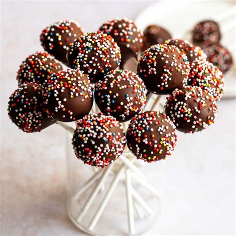 Imagen de cake pops terminados con una cobertura crujiente de chocolate y decoración de granillo sobre una mesa decorada