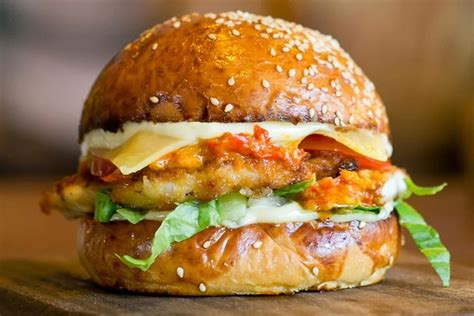 Foto de hamburguesa de pollo casera bien cocida con acompañamientos frescos.
