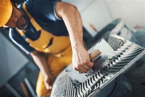 Imagen de un técnico preparando un adhesivo en polvo en un cubo, mezclando con una batidora