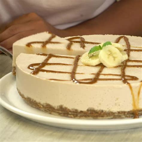 Cheesecake de plátano horneado decorado con dulce de leche, rodajas de plátano y nueces