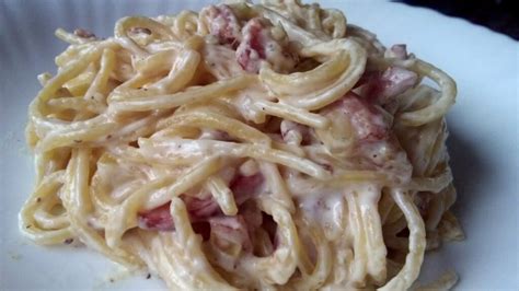 Fotografía de un plato de espaguetis con salsa cremosa, bacon y queso parmesano