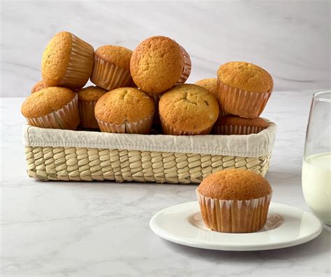 Foto temática de mantecadas caseras recién horneadas en una mesa rústica, con una taza de café o té al lado.