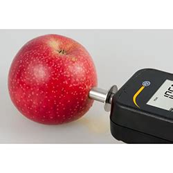 Fotografía de un penetrómetro manual midiendo la firmeza de la pulpa de una manzana.