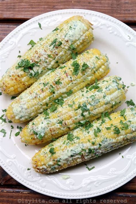 Foto en primer plano de choclo asado untado generosamente con salsa de queso y cilantro.