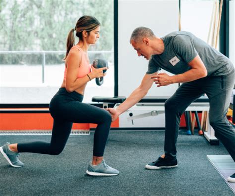 Entrenador personal demostrando un ejercicio a un cliente en un gimnasio