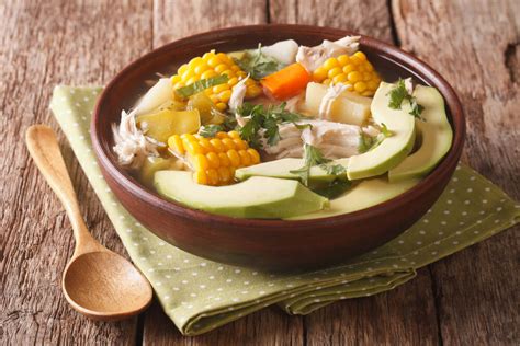 Ajiaco servido en plato hondo con hierbas frescas y huevo cocido