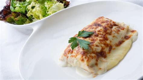 Plato de crepes rellenos de verduras gratinados con una capa dorada de queso fundido