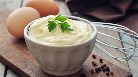 Mayonesa de ajo casera en un bol con ingredientes frescos alrededor