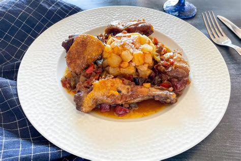 Plato de pato estofado con guarnición y salsa, mostrando su textura y color dorado