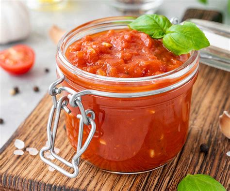 Foto de una olla con salsa de tomate casera burbujeando a fuego lento con hierbas frescas